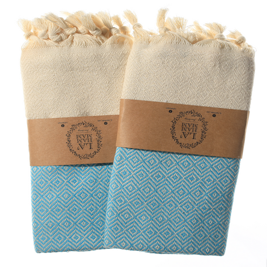 Turquoise diamond weave Turkish cotton towels with tan fringe, folded neatly side by side.